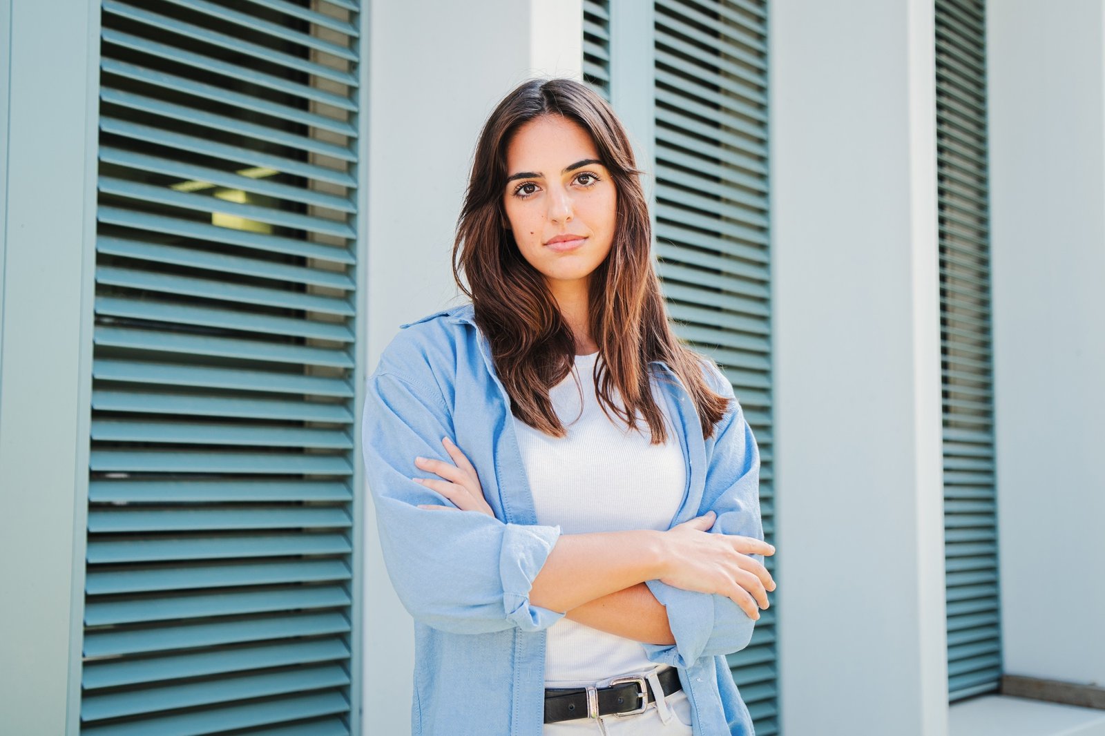 Caucasian serious young female student with arms crossed looking pensive at camera in casual clothes