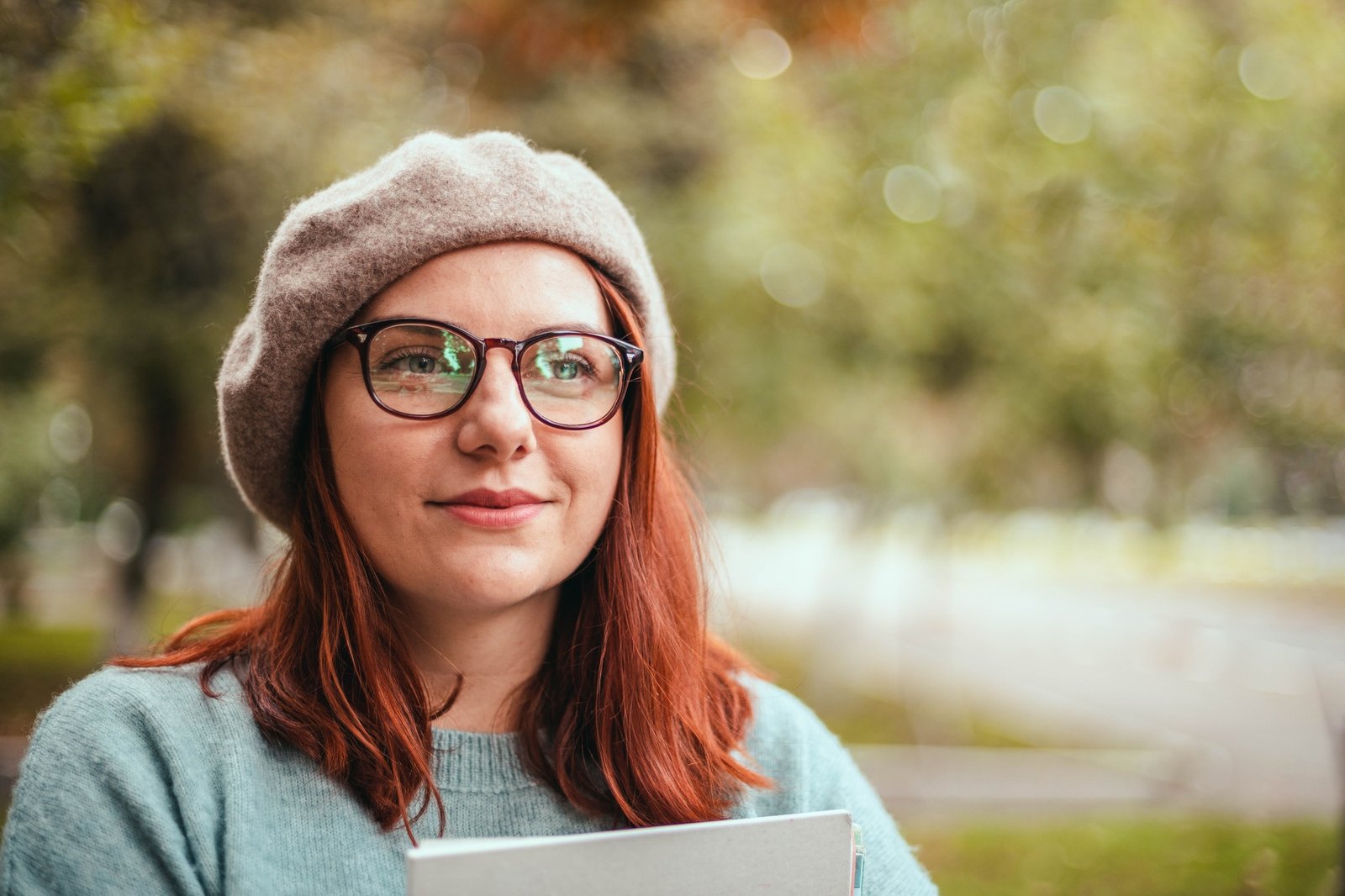 Cheerful female student in glasses looks at camera in the park